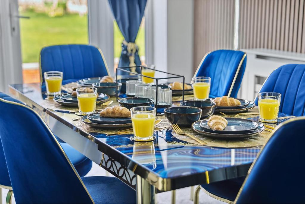 a table with plates of food and orange juice at 7 Bedroom Luxury House sleep 26 in Birmingham
