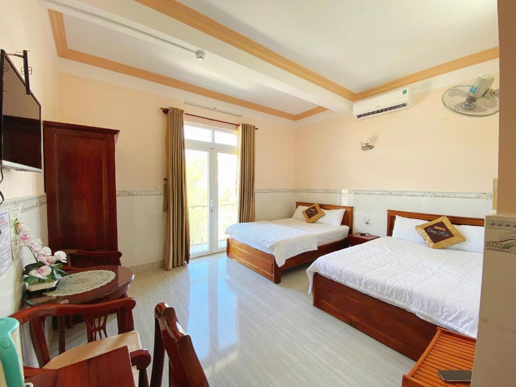 Un dormitorio con dos camas y una mesa y una ventana. en Trung Hậu Hotel, en Con Dao
