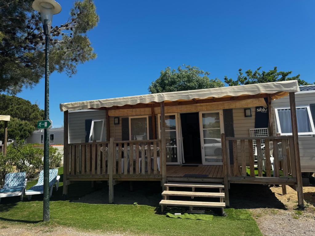 a tiny house with a porch and a deck at Mobile home Le Badwill2 in Canet-en-Roussillon