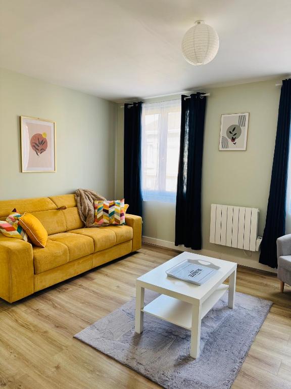 a living room with a yellow couch and a coffee table at Le Gari, Limoges in Limoges