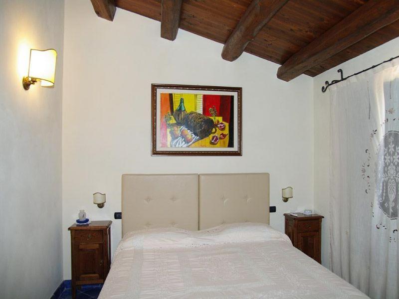 Un dormitorio con una cama blanca con una foto en la pared en Turismo Rurale Cefalù en Cefalù