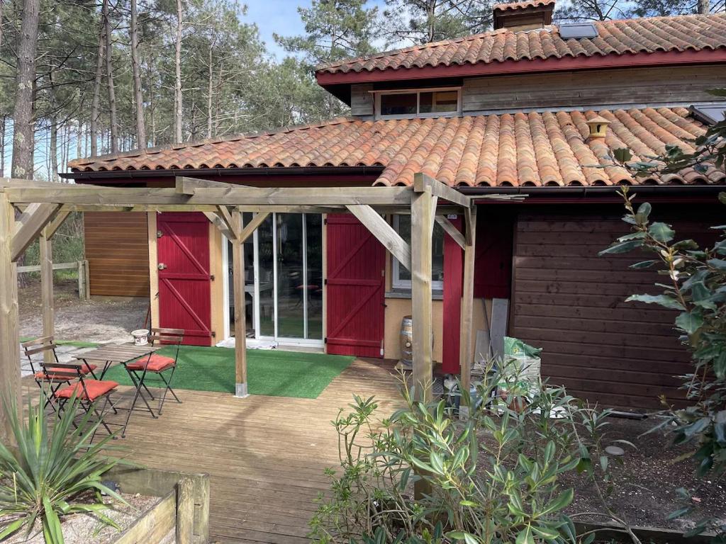 Maison dans la Pinède à Lacanau في لاكانو: منزل بأبواب حمراء وسطح خشبي