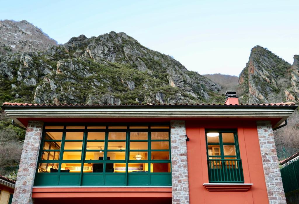 a building with a mountain in the background at Roca de Guía Somiedo in Pola de Somiedo