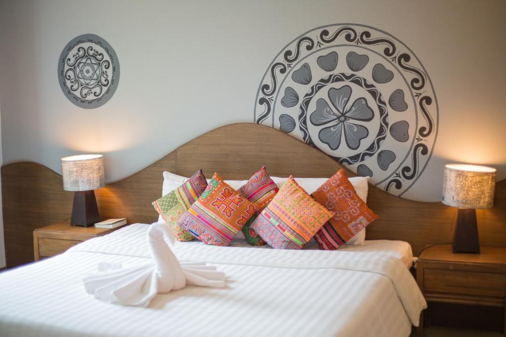 um quarto com uma cama grande e almofadas coloridas em The Opium Chiang Mai em Chiang Mai