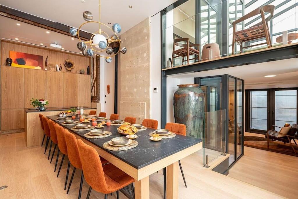 une salle à manger avec une grande table et des chaises orange dans l'établissement Haut Marais - My Skydome in Paris, à Paris