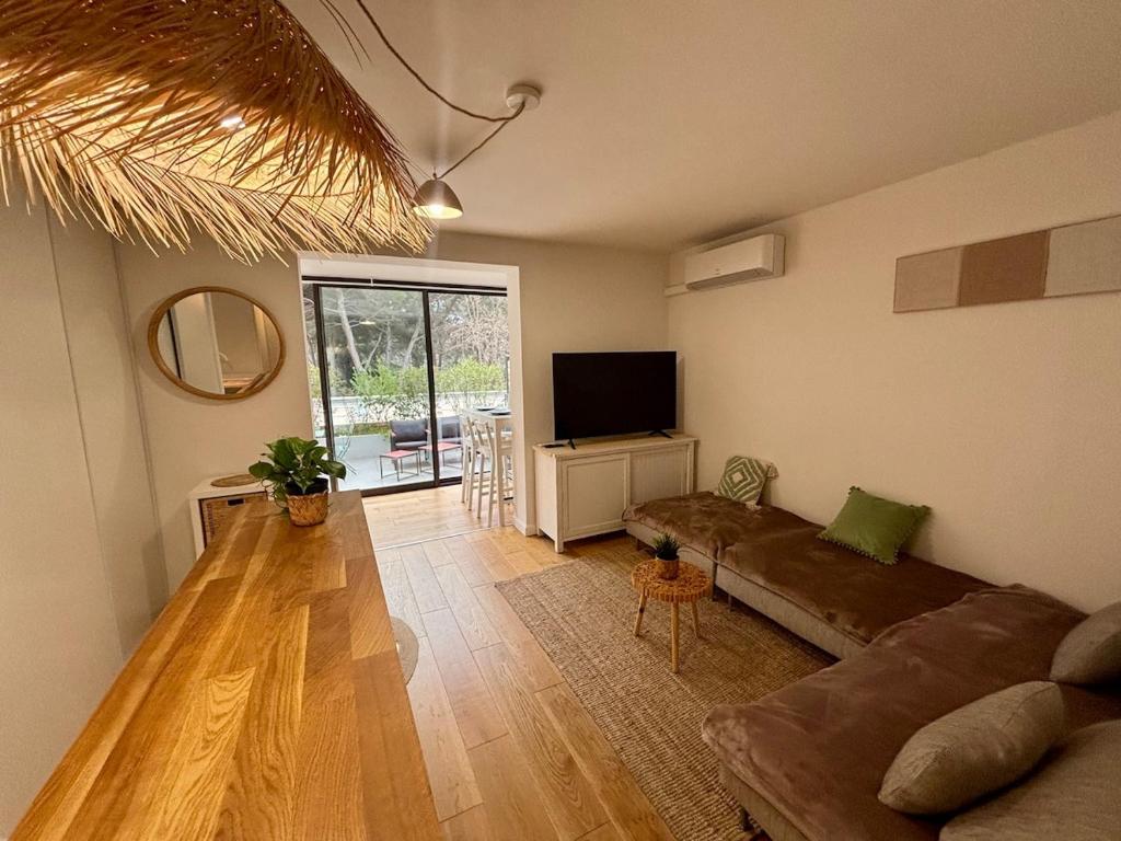 un salon avec un canapé et une télévision à écran plat dans l'établissement T2 en rez-de-jardin avec terrasse privative, résidence avec piscine et tennis, à Six-Fours-les-Plages