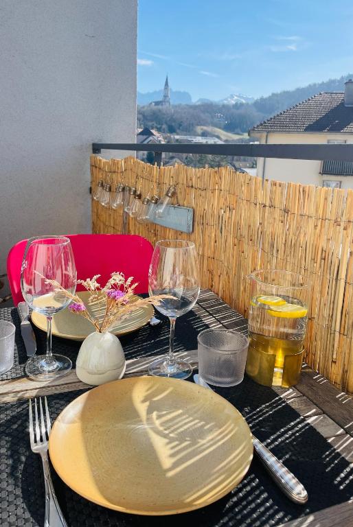 une table avec des assiettes et des verres à vin sur un balcon dans l'établissement L'Isernon, appartement avec balcons et garage, à Annecy