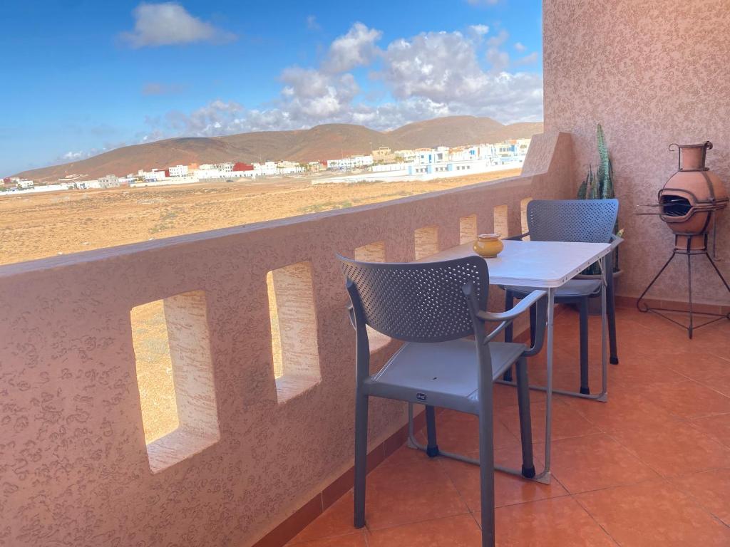 een tafel en stoelen op een balkon met uitzicht op het strand bij Tawada in Mirleft