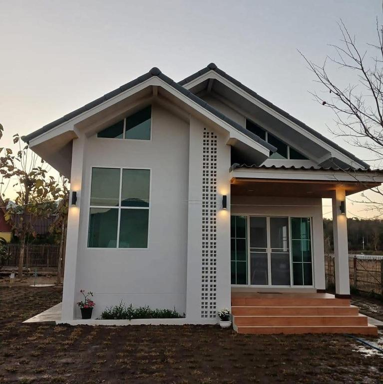 a small white house with a porch at บ้านสวนสุรัชฎา ปาย in Kampong Huaibū