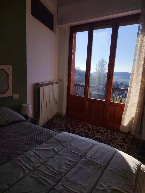 a bedroom with a bed and a large window at Debby Appartamenti in Montepulciano