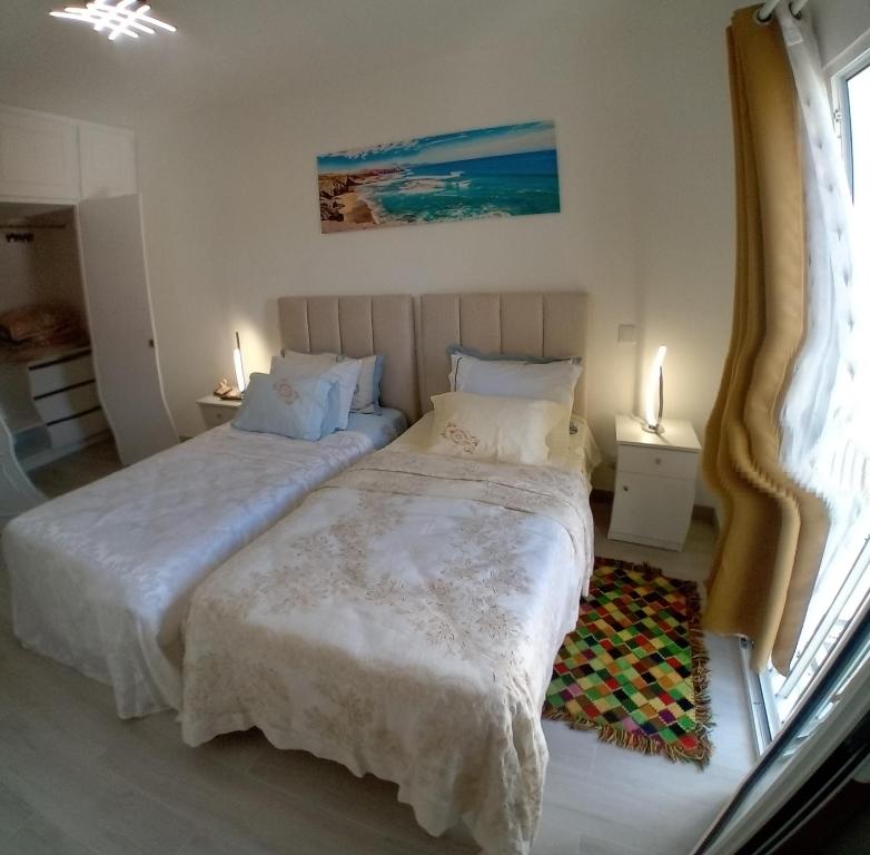 2 camas en un dormitorio con 2 lámparas en las mesas en apartamento Zarco, en Machico