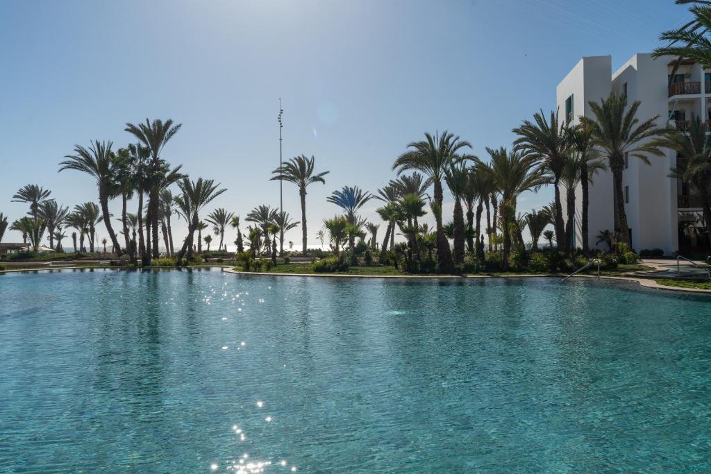 a pool of water with palm trees and buildings at The View Agadir in Agadir