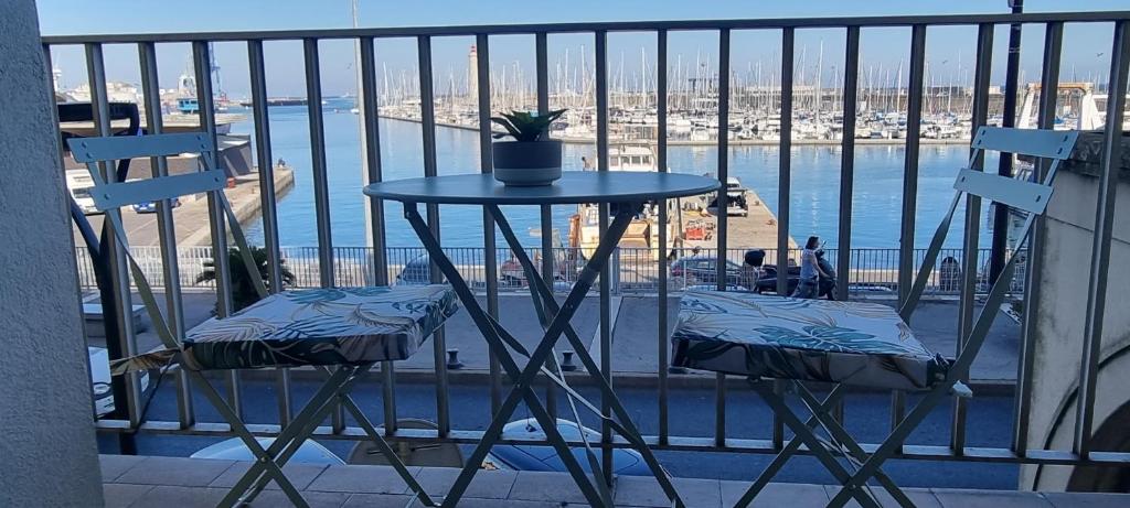 une table et des chaises sur un balcon avec vue sur l'eau dans l'établissement Le Môle, à Sète