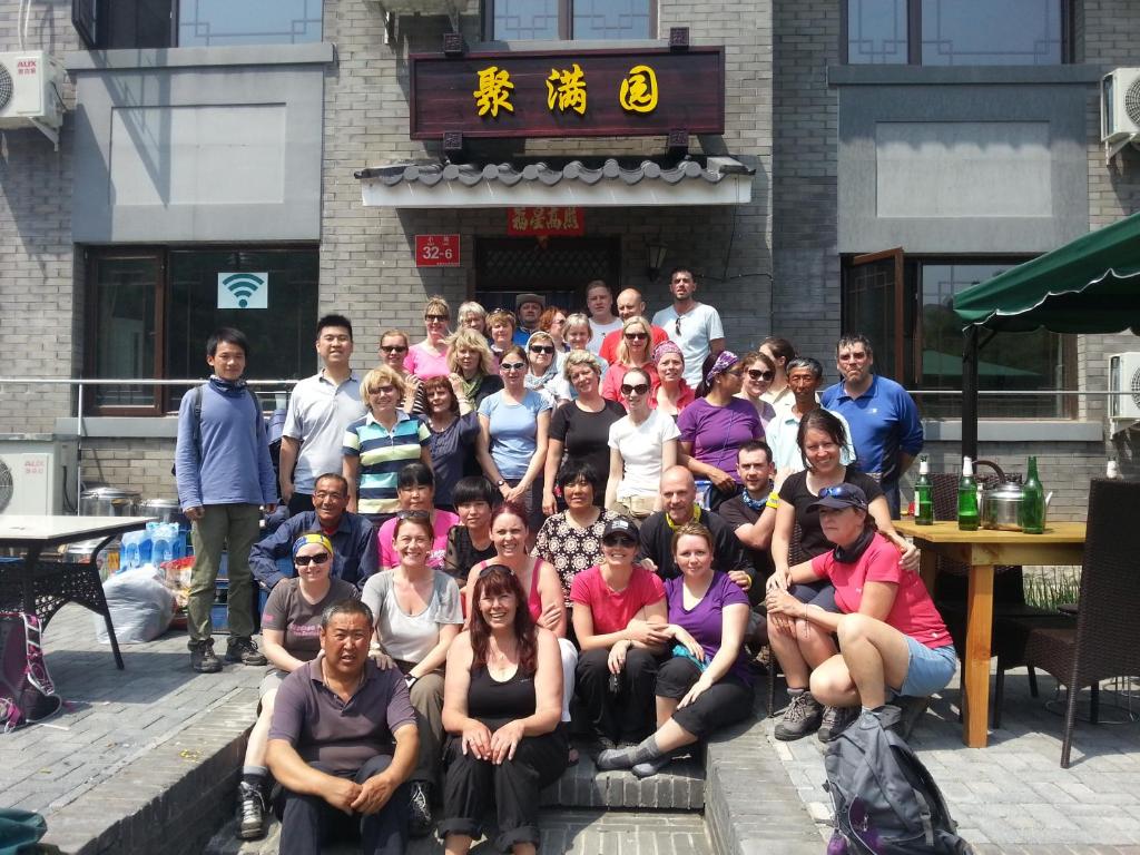un grupo de personas posando para una foto frente a un edificio en Jumanyuan House en Miyun