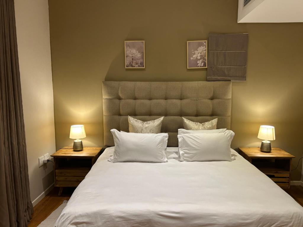 ein Schlafzimmer mit einem großen weißen Bett mit zwei Lampen in der Unterkunft Lofty-Space in Gaborone