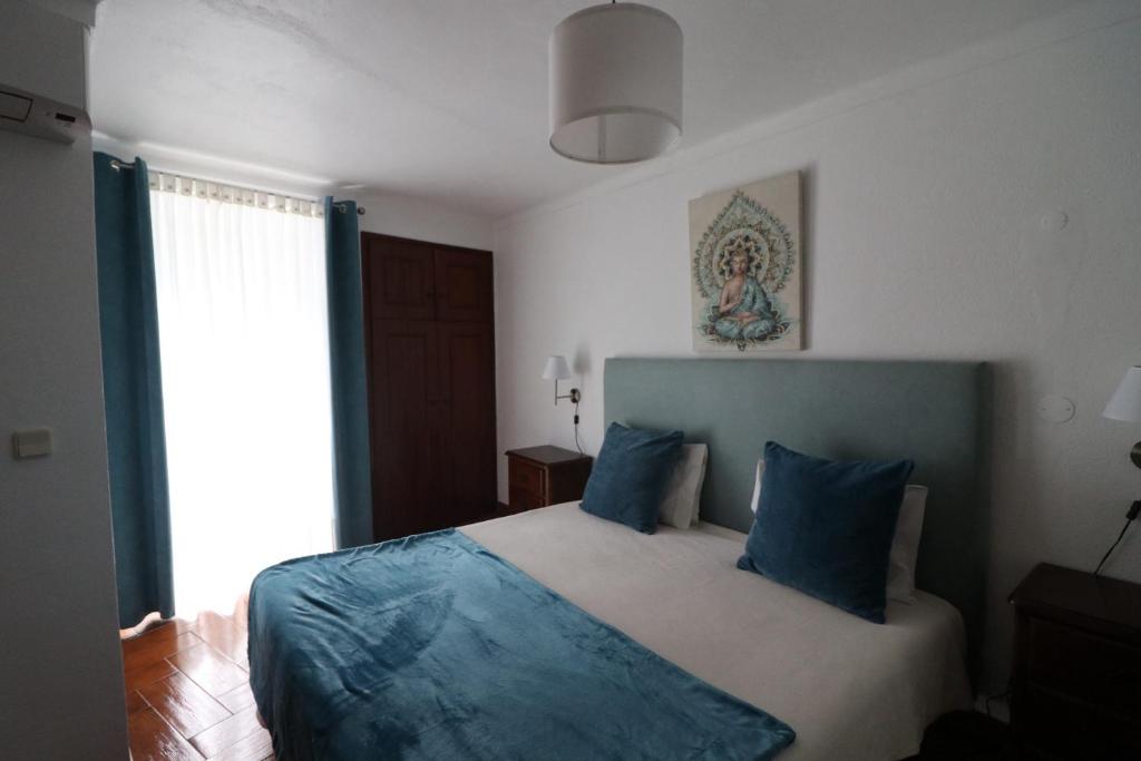 a bedroom with a bed with blue pillows and a window at Residencial Miguel José in Estremoz