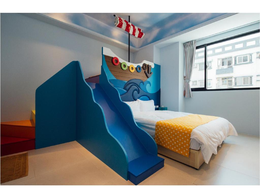 a bedroom with a blue bed with a painting of a waterfall at Yellow Kite Hostel in Tainan