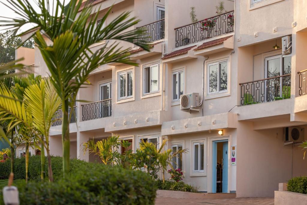 an apartment building with balconies and a palm tree at Alaya Stays Cavalo Marinho - 3 BHK Boho Retreat with Private Pool & Terrace in Camorlim