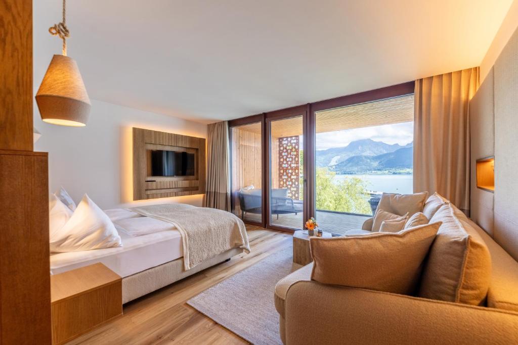 a hotel room with a bed and a large window at Hotel Seevilla Wolfgangsee in St. Wolfgang