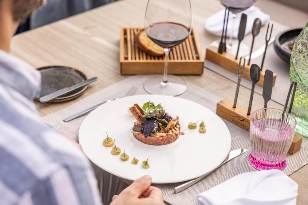 a table with a plate of food and a glass of wine at Hotel Seevilla Wolfgangsee in St. Wolfgang