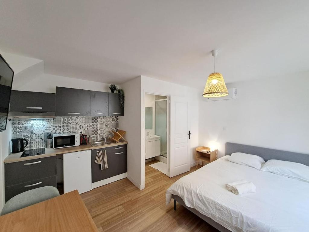 Cet appartement comprend une chambre avec un lit blanc et une cuisine. dans l'établissement Naples - Studio centre-ville, à Reims