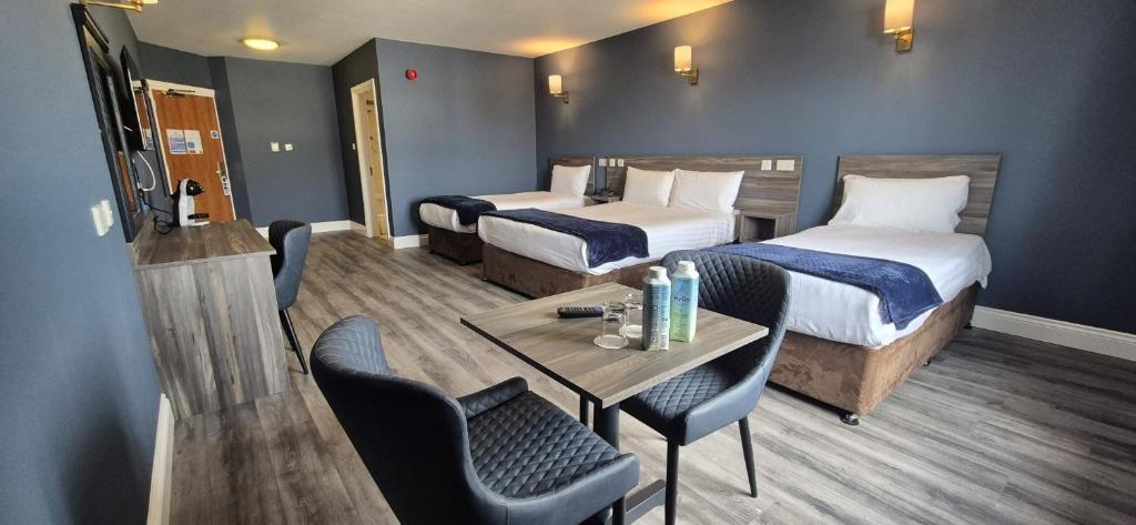 a hotel room with two beds and a table and chairs at Inn On The Coast in Portrush