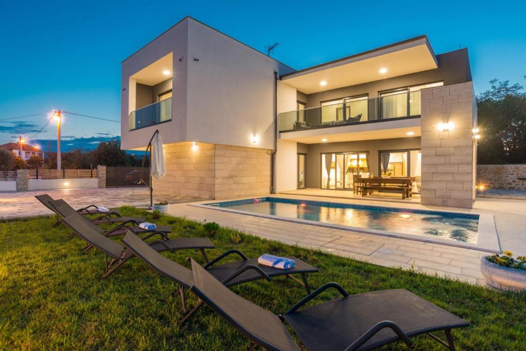 a villa with a swimming pool and chairs in the yard at Villa F&A ZadarVillas in Donje Raštane