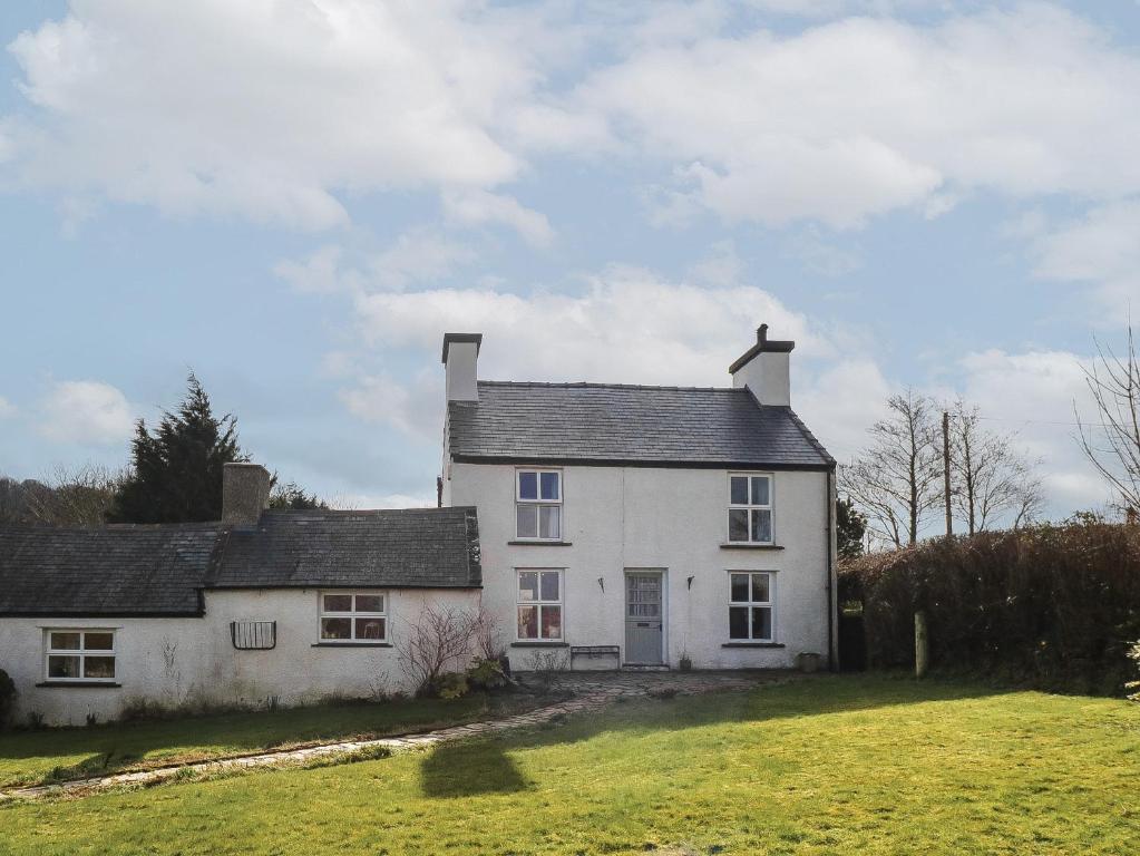 a large white house on a grassy field at Melin Rhos Farm in Penrhos-Lligwy