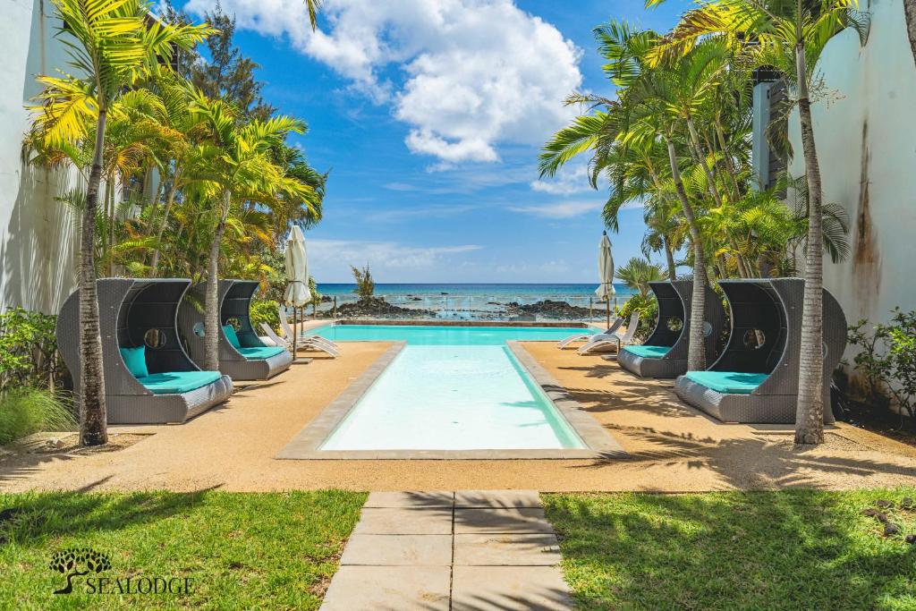 a pool at the beach with palm trees and chairs at Kanope Bay - Holiday Beachfront Apartments in Pointe aux Biches