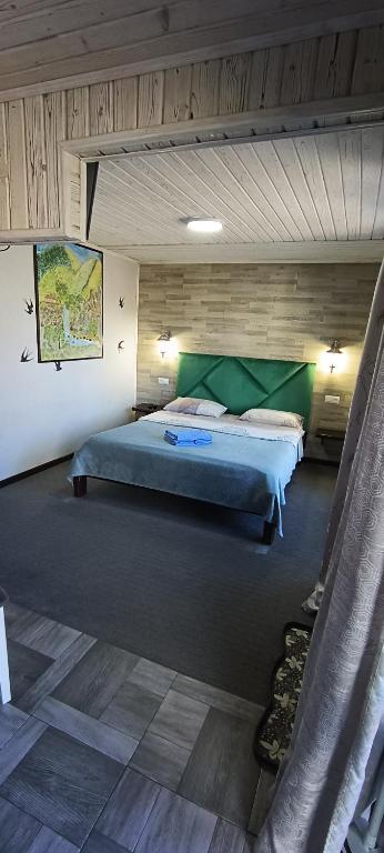 a bedroom with a large bed with green sheets at Садиба Янчар Номер Студiо з Басейном in Mykulychyn