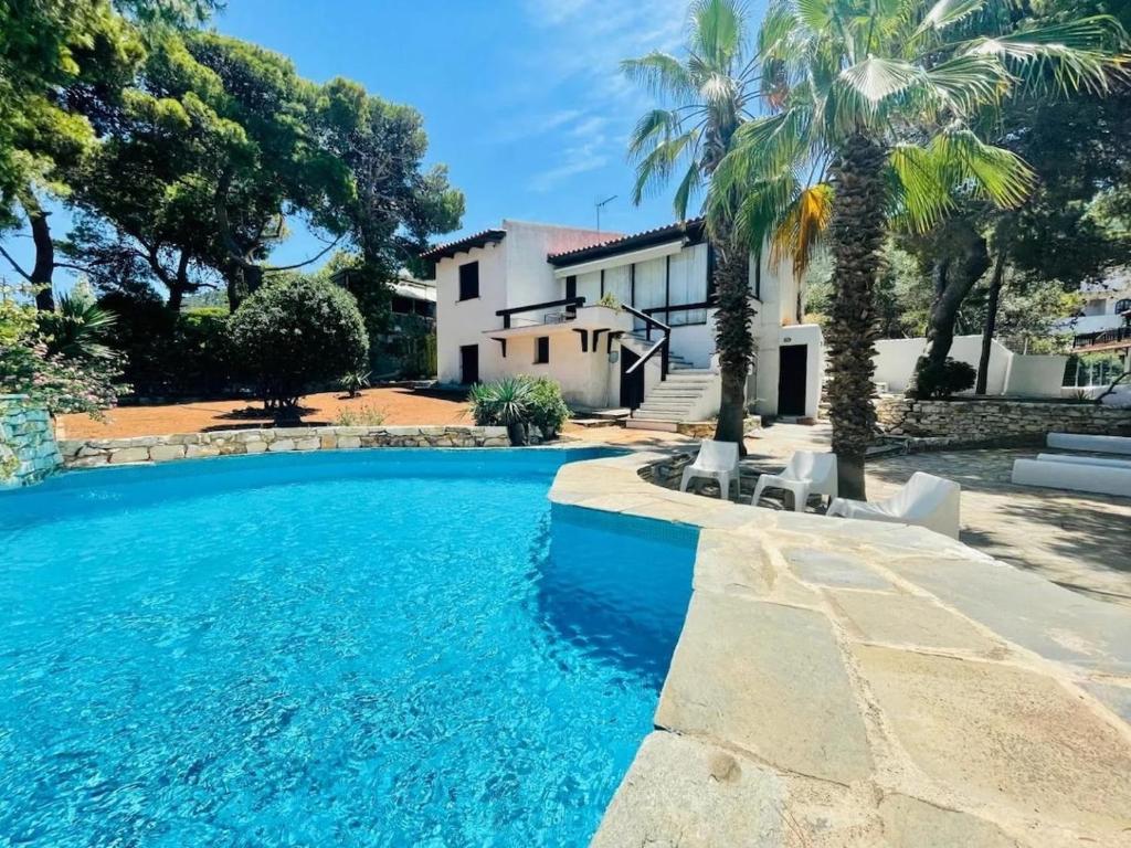 ein Swimmingpool vor einem Haus mit Palmen in der Unterkunft Villa Pharaoh Private Pool Near the Beach in Porto Rafti