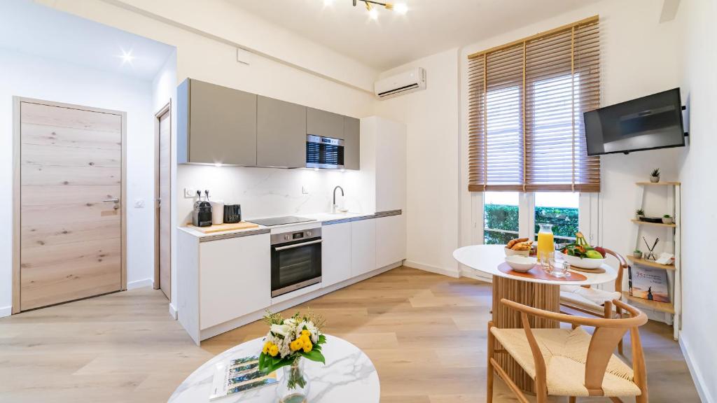 une cuisine avec des armoires blanches, une table et une table sidx sidx sidx dans l'établissement B G Cocon Meyerbeer - Grimaldi Promenade des Angla, à Nice