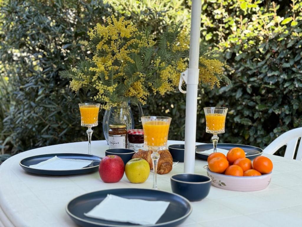 une table avec des assiettes de fruits et des verres de jus d'orange dans l'établissement Kakatoès - Studio à 500m des plages, à Mimizan-Plage