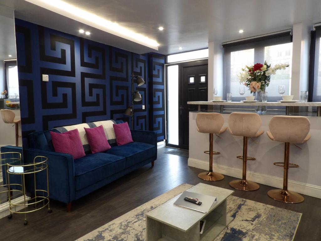 ein Wohnzimmer mit einem blauen Sofa und rosa Kissen in der Unterkunft City Convenience, Calm Comfort-- A Stylish One-Bedroom Retreat Just 3 Stops from the Heart of the City in Edinburgh