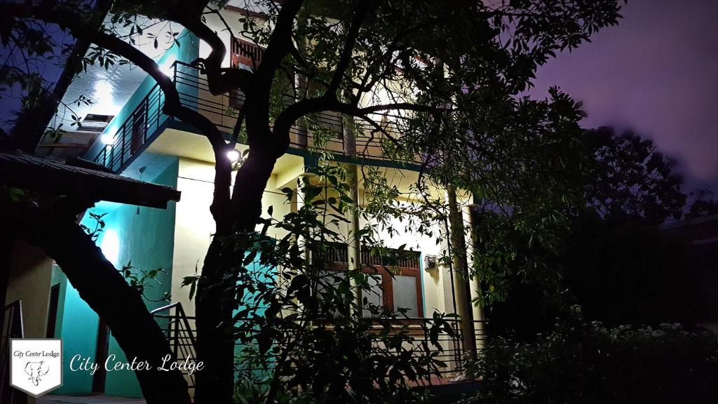 un bâtiment avec un arbre devant lui la nuit dans l'établissement City Centre Lodge, à Anurâdhapura