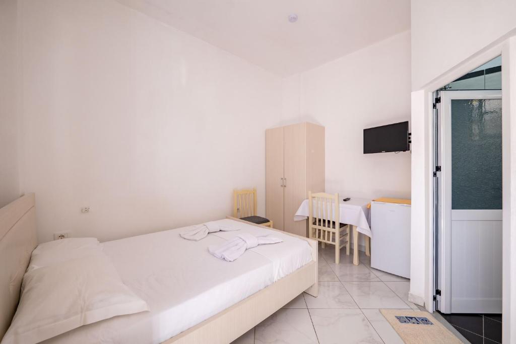 a white bedroom with a bed and a table at Vila Celi in Sarandë