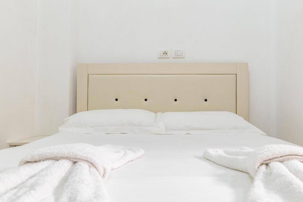 a white bed with two white towels on it at Vila Celi in Sarandë