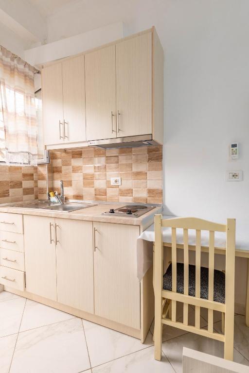 a kitchen with white cabinets and a sink and a table at Vila Celi in Sarandë
