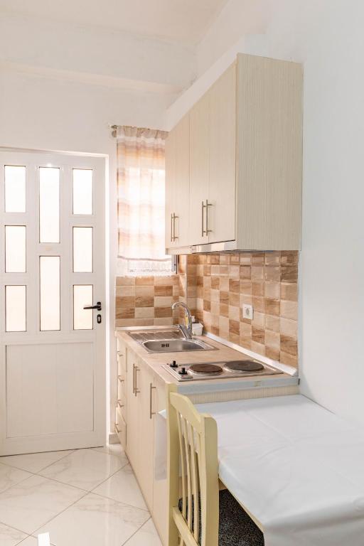 a kitchen with white cabinets and a sink and a door at Vila Celi in Sarandë