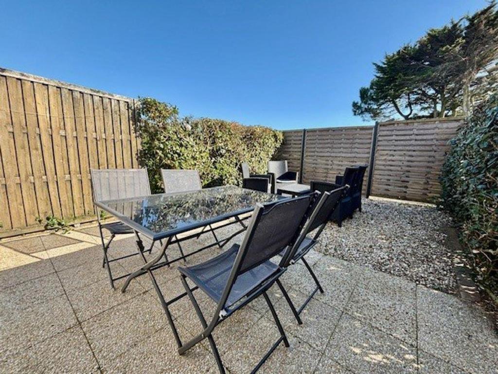 une table en verre et des chaises assises sur une terrasse dans l'établissement Maison à Quiberon 3 pièces avec piscine, proche plage et commerces - FR-1-478-60, à Quiberon