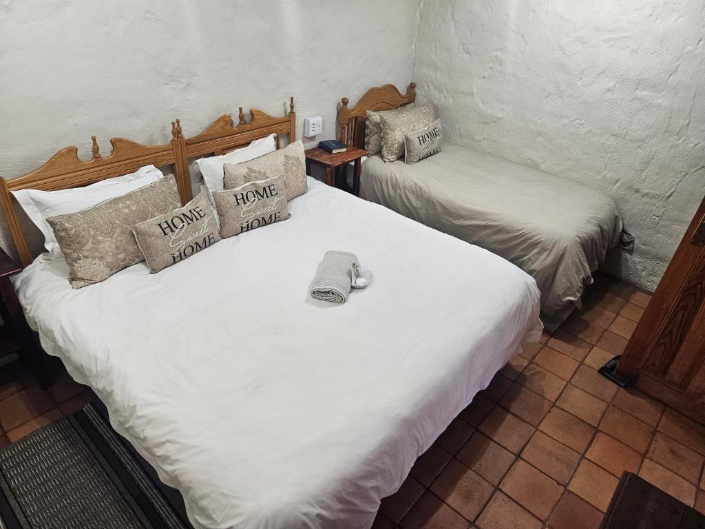 zwei Betten in einem Zimmer mit weißen Laken in der Unterkunft Melville Guesthouse & Contractors Lodge in Lichtenburg