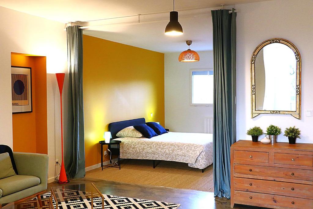 a bedroom with a bed and a chair and a dresser at Plain pied cosy à 20 minutes de bordeaux - Le Clos Montichamp in Camblanes-et-Meynac