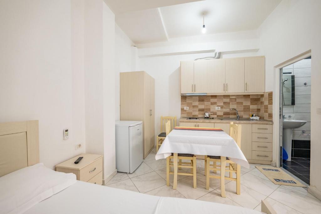 a kitchen with white cabinets and a table with chairs at Vila Celi in Sarandë