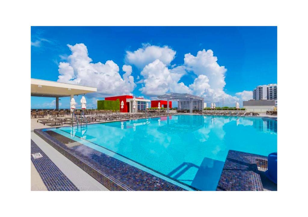 a large blue swimming pool with chairs and buildings at A Fantastic apart with balcony and partial view of the beach 4 Px in Hollywood