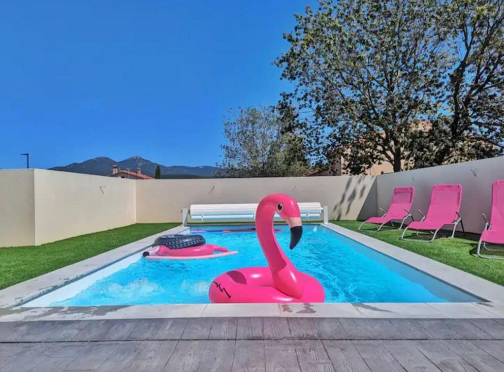 un flamingo rose dans une piscine avec des chaises roses dans l'établissement Villa 8 pers, Piscine privée, proche mer, à Maureillas