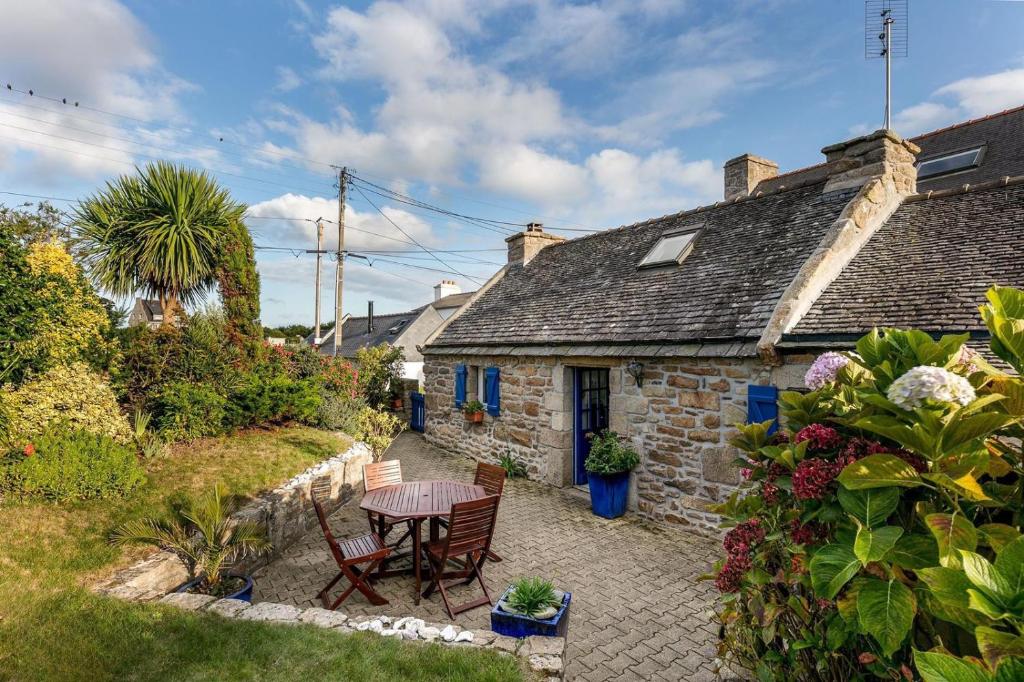 a stone cottage with a table and chairs in a yard at Charmante maison en pierre - vue sur l'océan in Lilia
