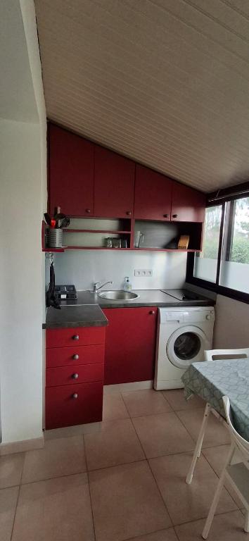 - une cuisine avec des placards rouges et un lave-linge dans l'établissement Studio Village Camarguais, à Arles