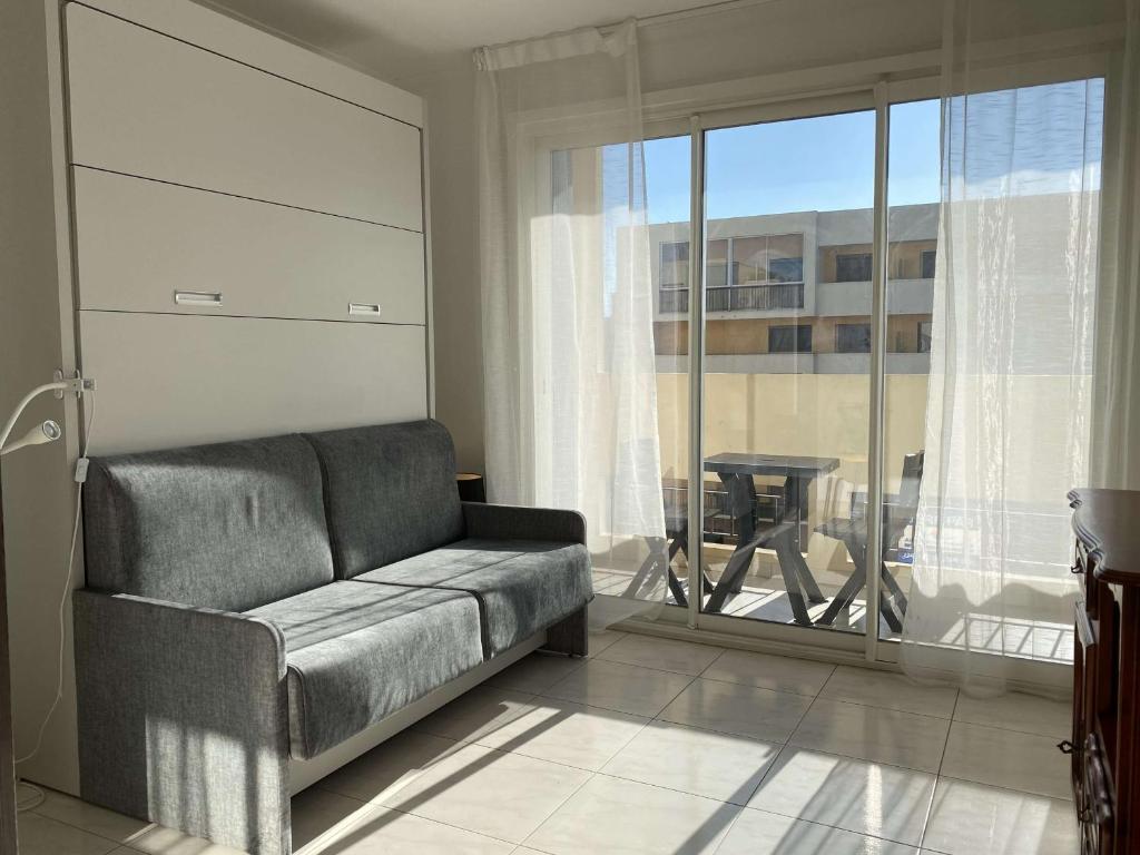 un salon avec un canapé et une grande fenêtre dans l'établissement Appartement T2 Lumineux à Balaruc-les-Bains, Proche Thermes, Parking, Wifi, 2 Étoiles - FR-1-553-130, à Balaruc-les-Bains