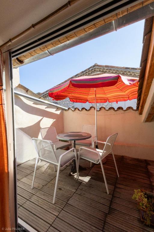un patio avec une table, des chaises et un parasol dans l'établissement Le Havre du Pastre, à Buis-les-Baronnies