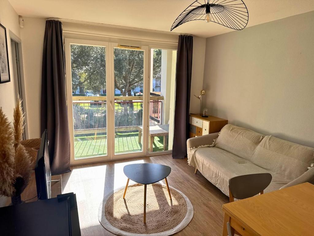 a living room with a couch and a large window at L'Eclat Terrasse - Piscine - Tennis in Ondres